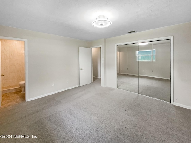 unfurnished bedroom featuring connected bathroom, a closet, and carpet