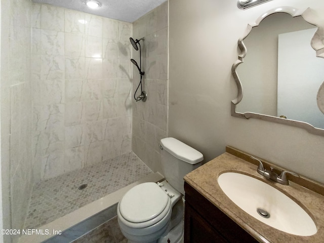 bathroom featuring toilet, vanity, and tiled shower