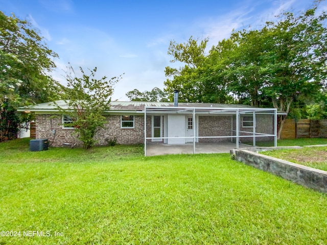 rear view of property with central AC and a lawn