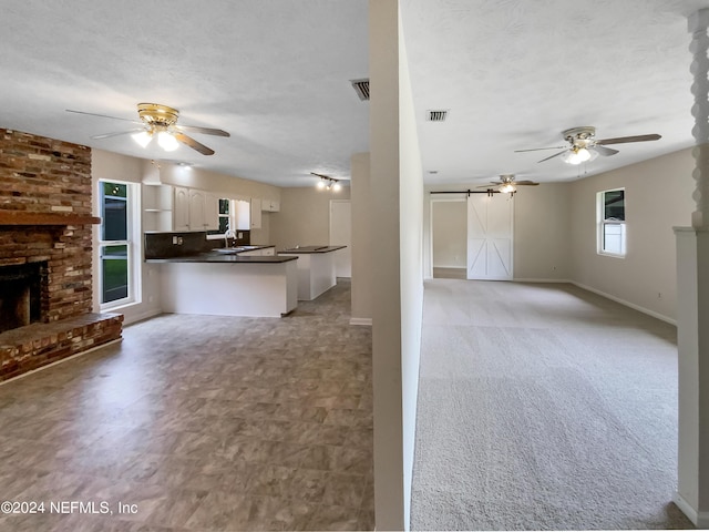 kitchen featuring sink, white cabinets, a fireplace, kitchen peninsula, and a barn door