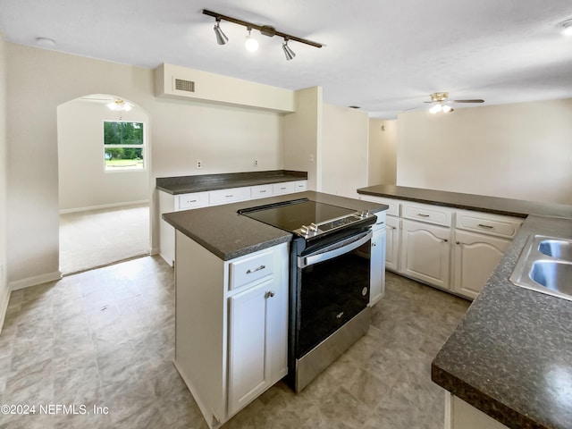 kitchen with track lighting, white cabinets, stainless steel electric range oven, ceiling fan, and sink