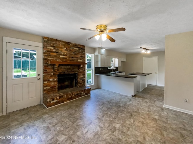 interior space with a brick fireplace, ceiling fan, a wealth of natural light, and sink