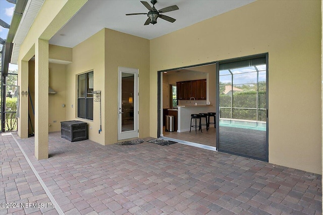 view of patio with ceiling fan, a lanai, and a bar