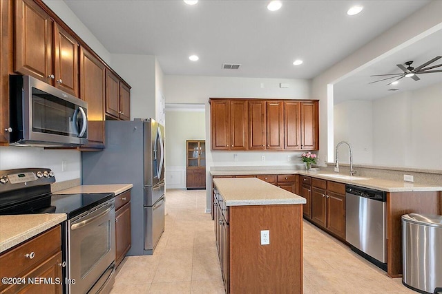 kitchen with kitchen peninsula, appliances with stainless steel finishes, ceiling fan, sink, and a center island