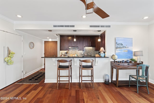 kitchen with dark brown cabinets, backsplash, hanging light fixtures, and dark wood-type flooring