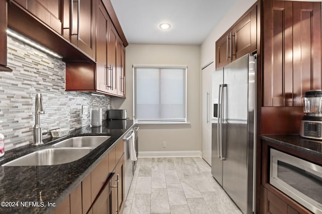 kitchen with dark stone countertops, decorative backsplash, sink, and appliances with stainless steel finishes