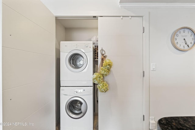 clothes washing area with crown molding and stacked washer / drying machine