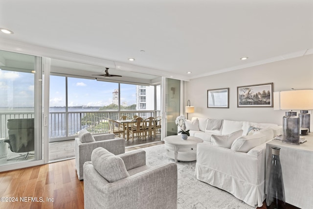 living room featuring hardwood / wood-style floors, ceiling fan, a water view, and ornamental molding