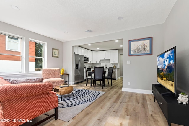 living room with sink, light hardwood / wood-style floors, and a textured ceiling