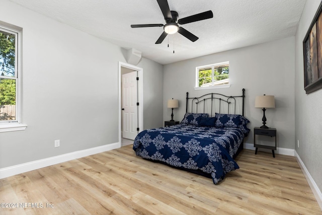 bedroom with ceiling fan, light hardwood / wood-style flooring, and a textured ceiling