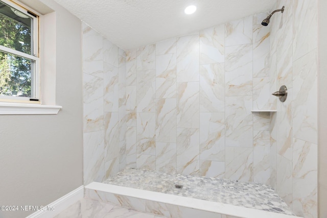 bathroom featuring tiled shower and a textured ceiling