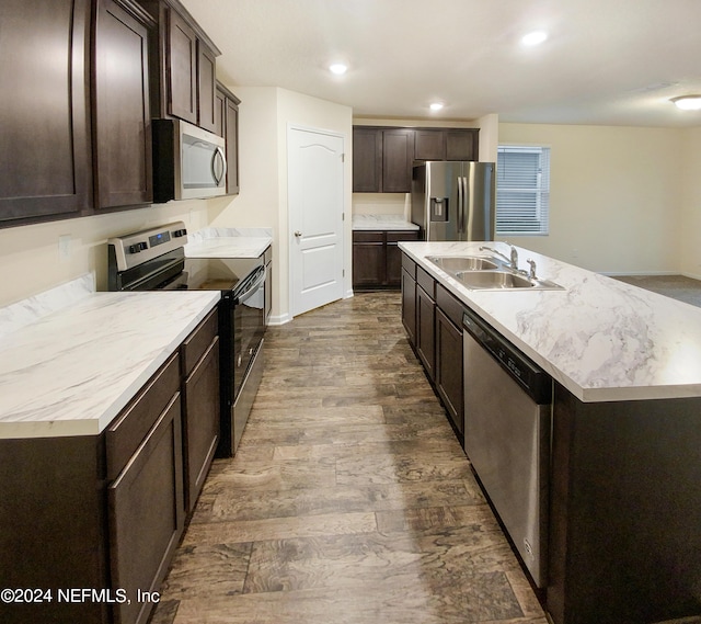 kitchen with hardwood / wood-style flooring, sink, dark brown cabinets, stainless steel appliances, and a center island with sink