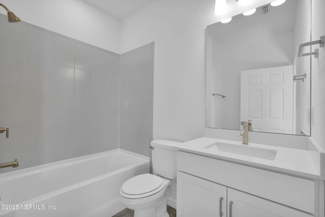 full bathroom featuring vanity, tiled shower / bath combo, and toilet