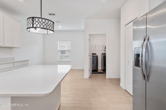 kitchen featuring white cabinetry, light hardwood / wood-style floors, stainless steel refrigerator with ice dispenser, separate washer and dryer, and pendant lighting