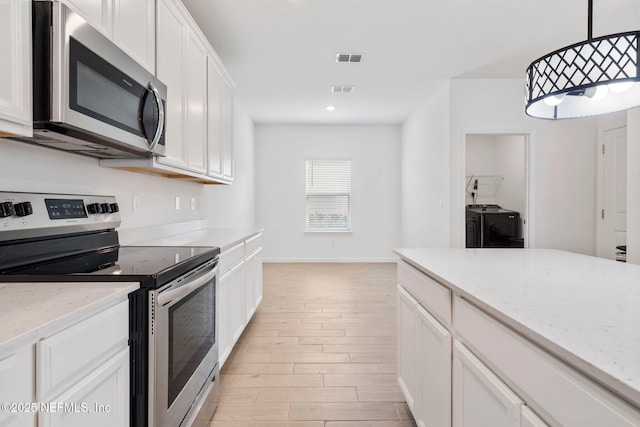 kitchen featuring white cabinetry, washer and clothes dryer, appliances with stainless steel finishes, pendant lighting, and light stone counters