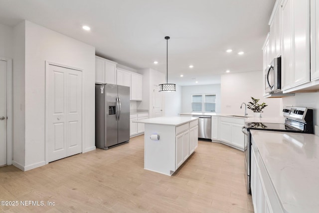 kitchen featuring decorative light fixtures, a center island, sink, light hardwood / wood-style flooring, and stainless steel appliances