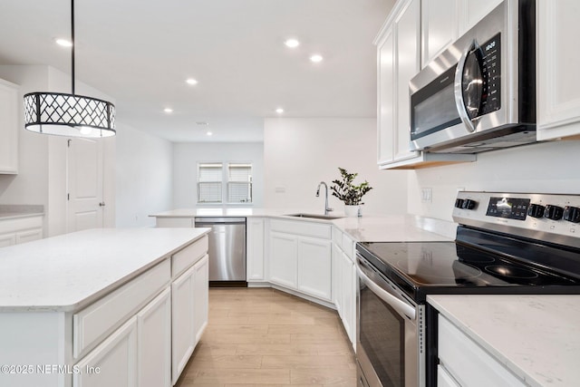 kitchen with pendant lighting, sink, white cabinets, and appliances with stainless steel finishes