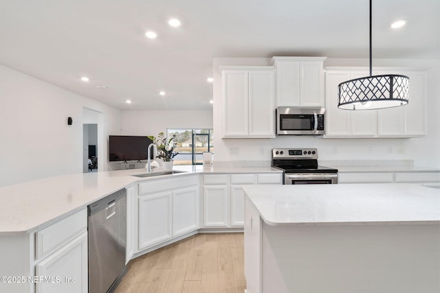 kitchen with stainless steel appliances, white cabinets, hanging light fixtures, and sink