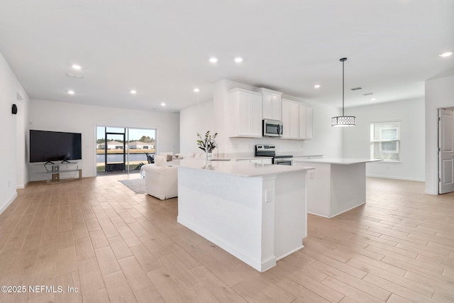 kitchen featuring kitchen peninsula, pendant lighting, stainless steel appliances, and white cabinetry