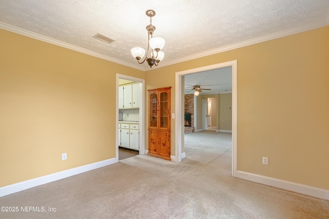 carpeted empty room with a fireplace, a textured ceiling, ceiling fan with notable chandelier, and ornamental molding