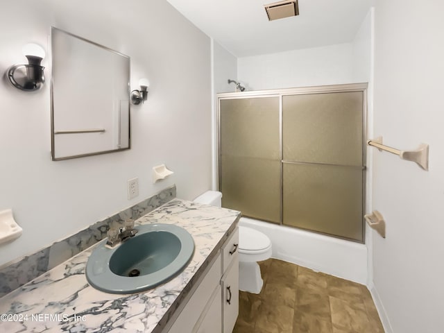 full bathroom with vanity, toilet, and bath / shower combo with glass door