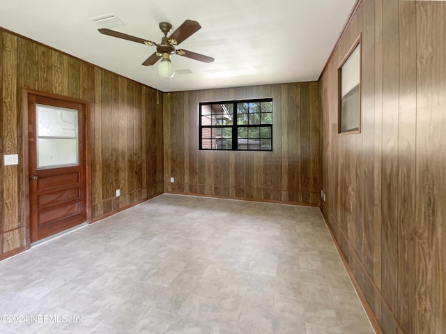 spare room featuring ceiling fan and wooden walls