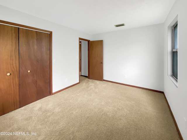 unfurnished bedroom featuring light carpet and a closet