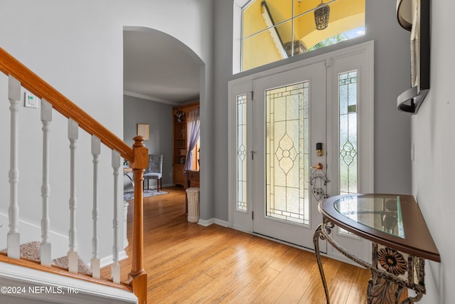 foyer entrance with light hardwood / wood-style flooring and crown molding