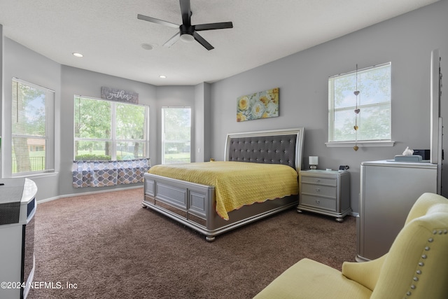 bedroom with a textured ceiling, ceiling fan, and dark colored carpet