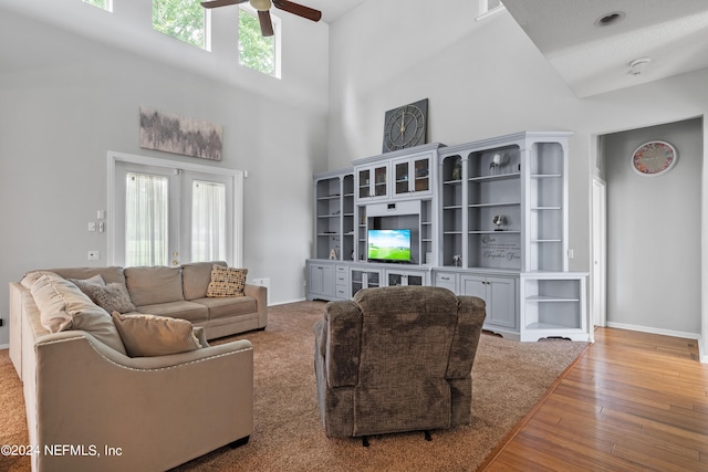 living room with a towering ceiling, light hardwood / wood-style flooring, french doors, and ceiling fan