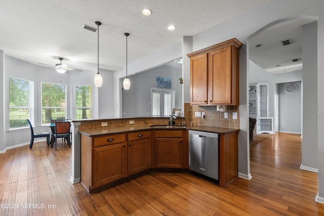 kitchen featuring sink, dishwasher, backsplash, wood-type flooring, and decorative light fixtures