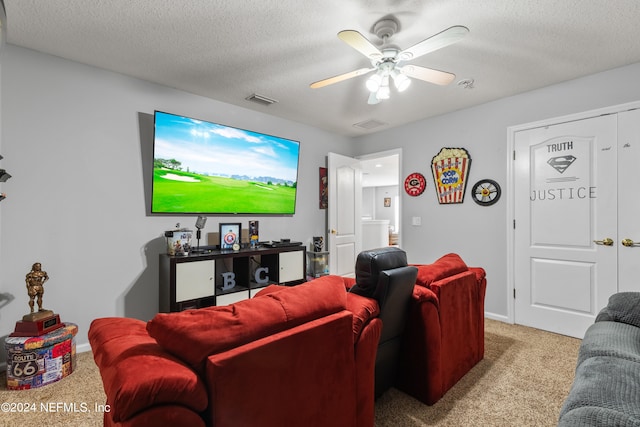 cinema room with ceiling fan, light carpet, and a textured ceiling