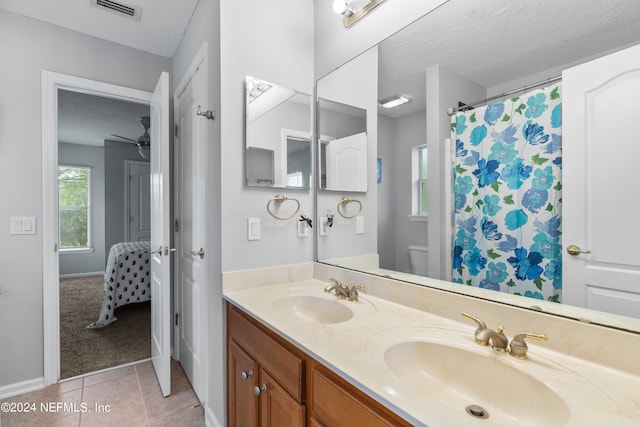 bathroom featuring vanity, toilet, tile patterned flooring, and a textured ceiling