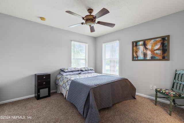 carpeted bedroom featuring ceiling fan and a textured ceiling