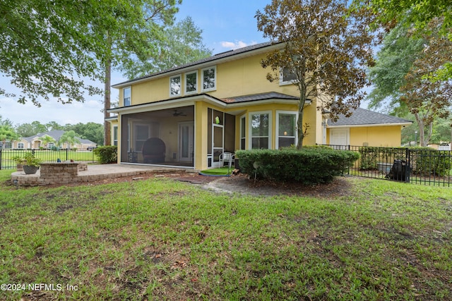 rear view of property featuring a yard, a patio area, a sunroom, and ceiling fan