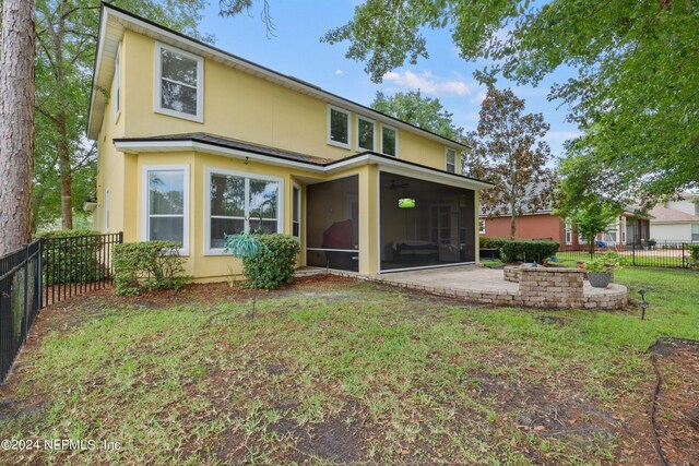 rear view of property featuring a patio, a sunroom, and a yard