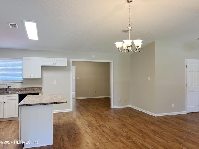 kitchen featuring a kitchen island, white cabinets, pendant lighting, and a notable chandelier