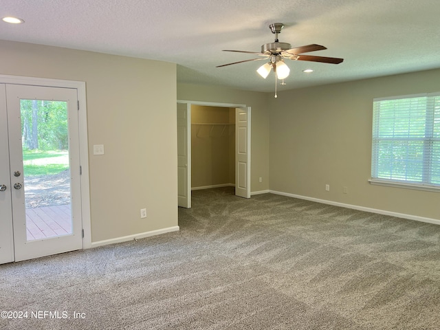 unfurnished bedroom with ceiling fan, multiple windows, access to outside, and a closet