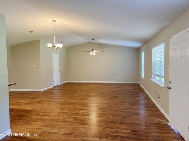 empty room with ceiling fan with notable chandelier, vaulted ceiling, and dark wood-type flooring