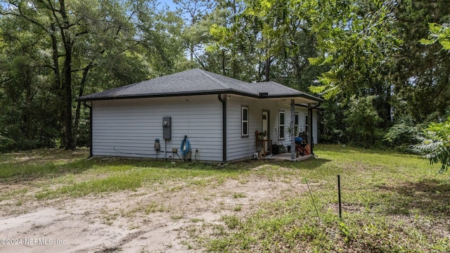 view of side of home featuring roof with shingles and a lawn