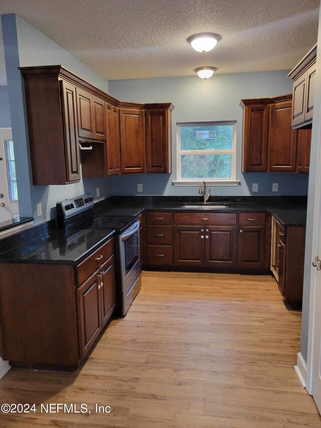 kitchen featuring stainless steel electric range, sink, light hardwood / wood-style flooring, a textured ceiling, and dark brown cabinets