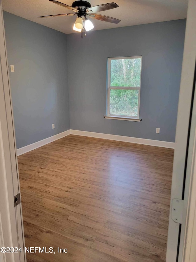 empty room featuring a ceiling fan, baseboards, and wood finished floors