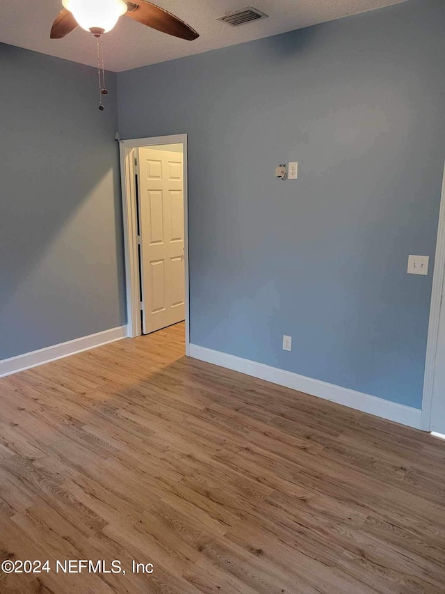 empty room with ceiling fan and light hardwood / wood-style floors