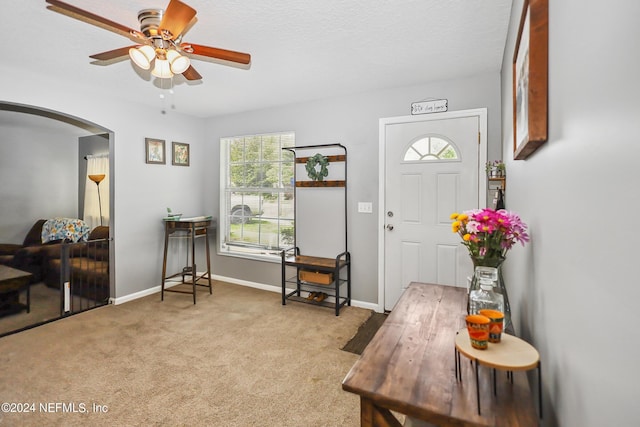 carpeted entryway with ceiling fan