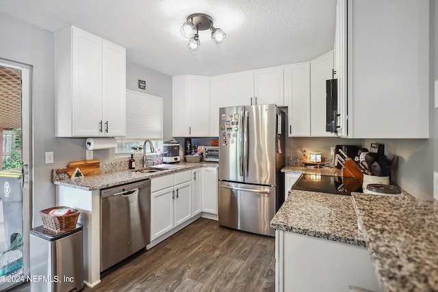 kitchen featuring white cabinetry, sink, light stone countertops, dark hardwood / wood-style floors, and appliances with stainless steel finishes