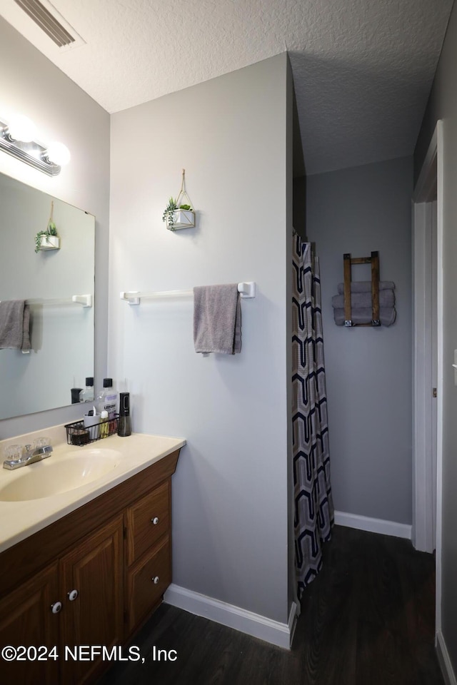 bathroom featuring vanity, wood-type flooring, and a textured ceiling