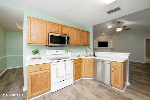 kitchen featuring appliances with stainless steel finishes, lofted ceiling, sink, and light hardwood / wood-style floors