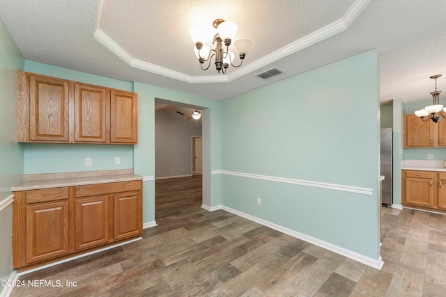 kitchen featuring a tray ceiling, wood-type flooring, a textured ceiling, ceiling fan with notable chandelier, and stainless steel refrigerator