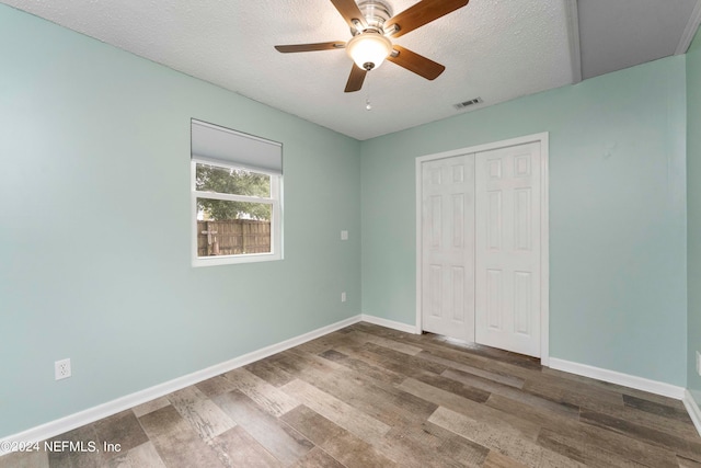 unfurnished bedroom with a closet, hardwood / wood-style floors, a textured ceiling, and ceiling fan