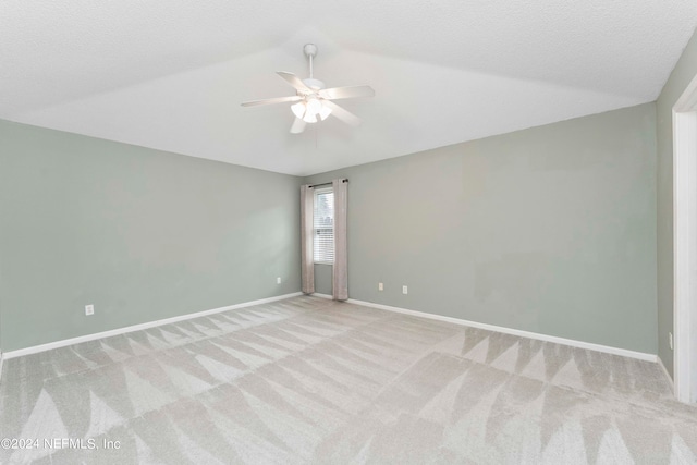 carpeted empty room featuring vaulted ceiling, a textured ceiling, and ceiling fan